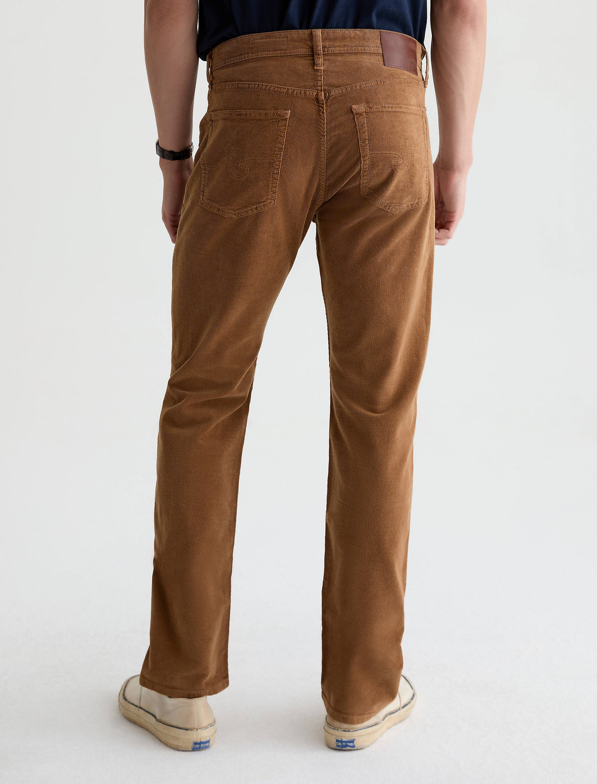 Back view of men's bronze brown corduroy straight-leg pants with leather patch detail