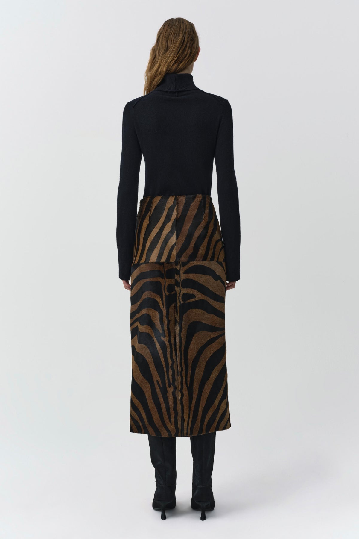Back view of black cashmere turtleneck sweater styled with zebra print midi skirt