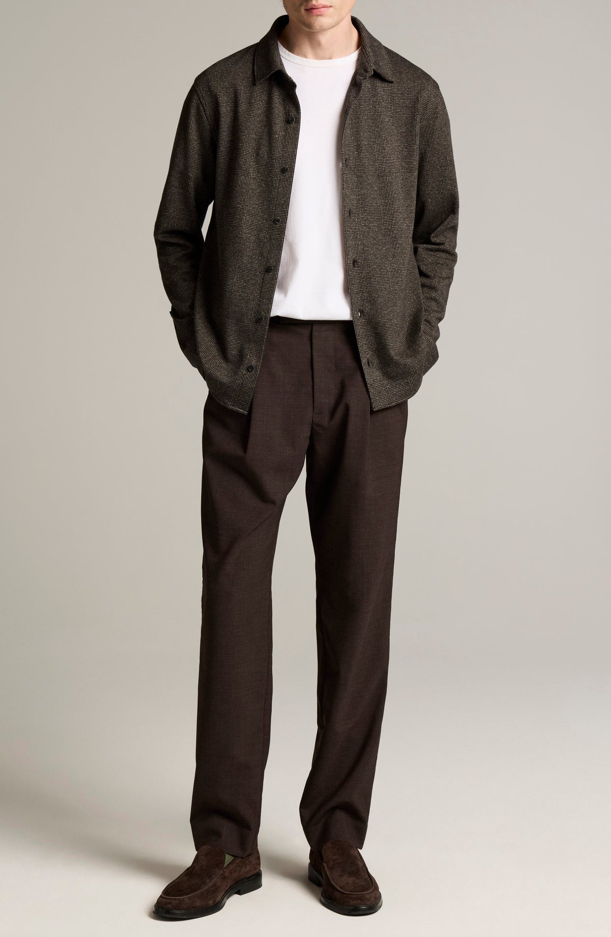 Male model wearing brown glen plaid button-down shirt over white tee with dark trousers