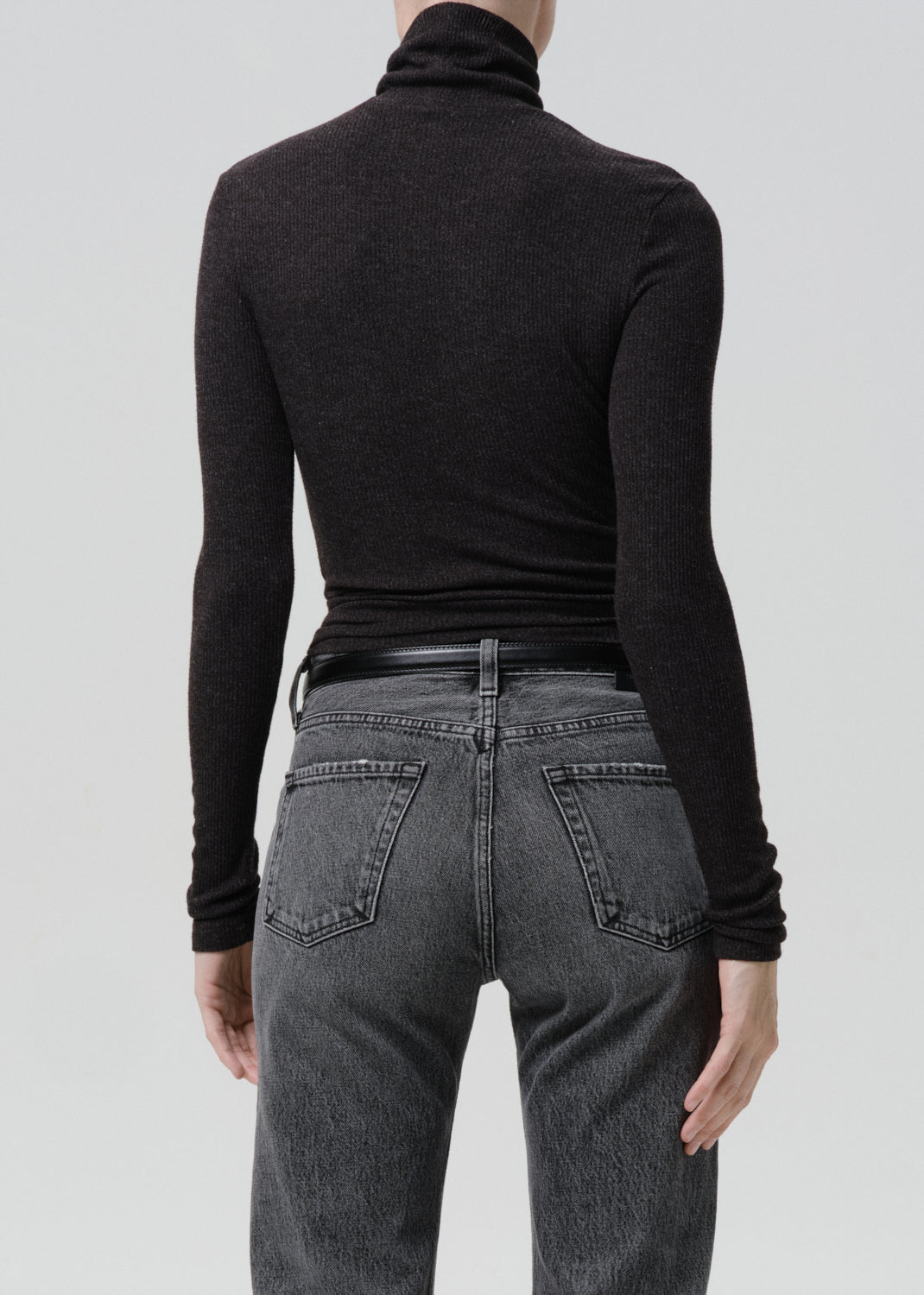 Back view of ribbed heather charcoal turtleneck with long sleeves paired with grey jeans