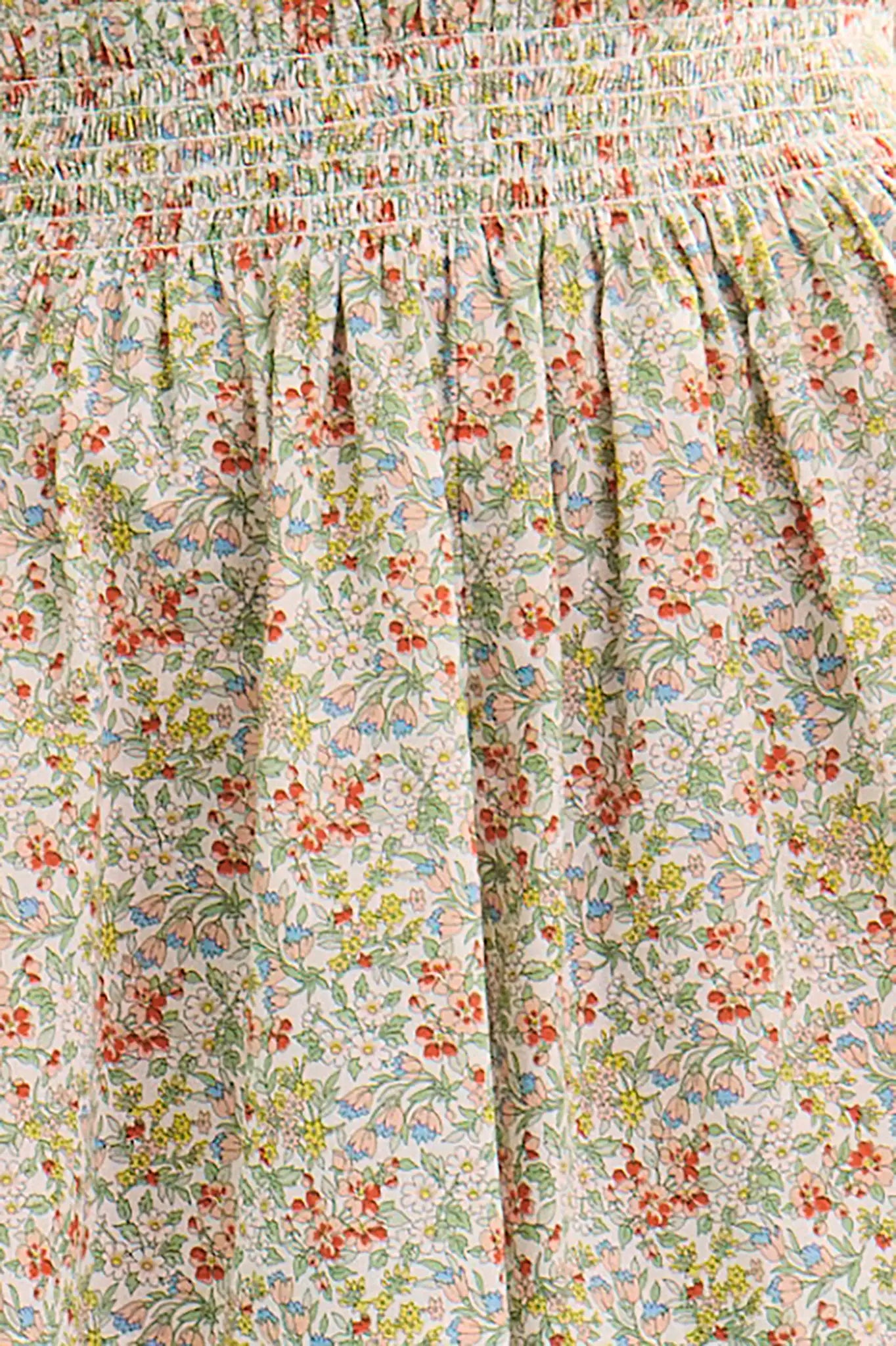 Close-up detail of floral print fabric with coral, green, and blue flowers on light background