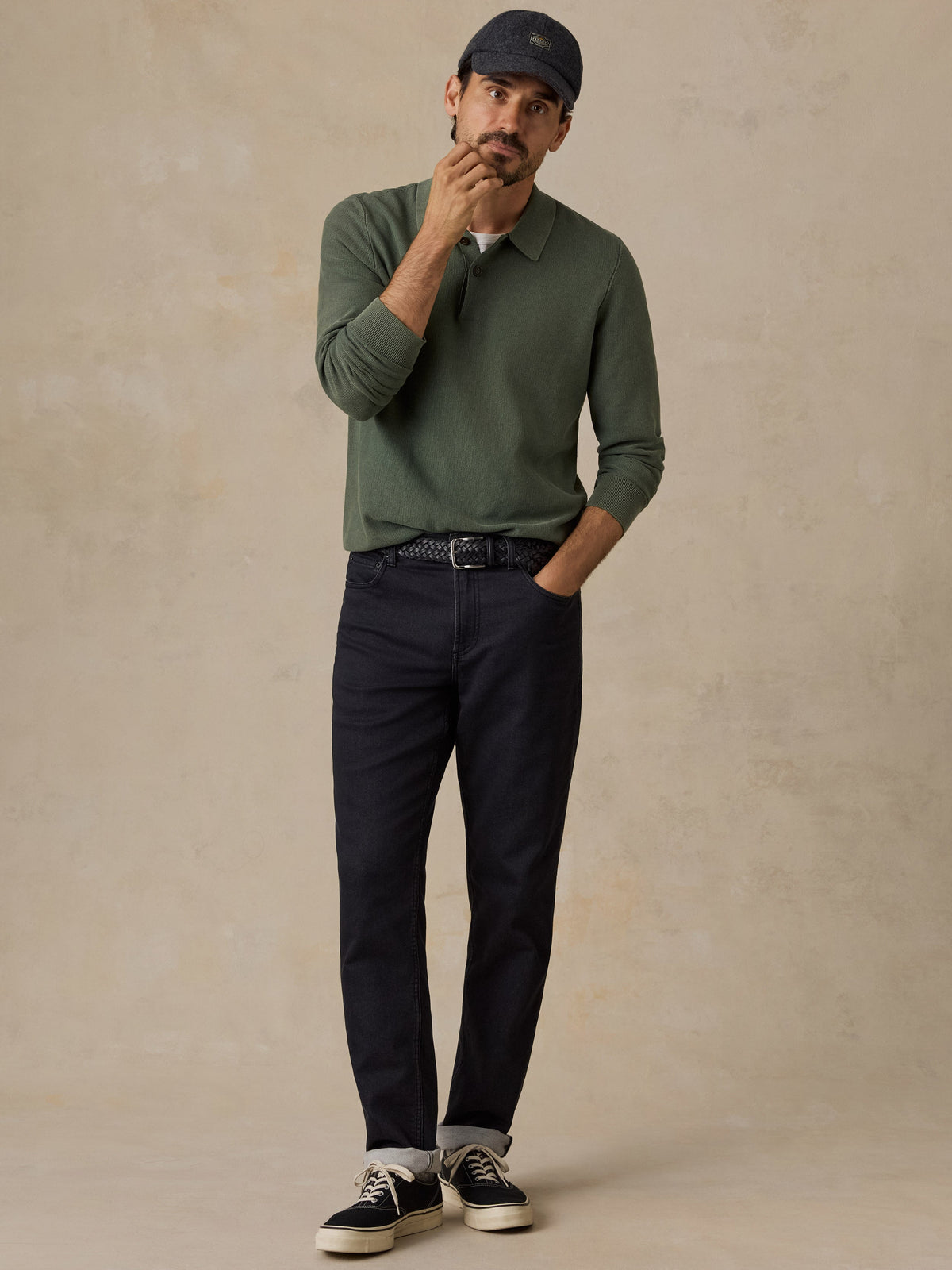 Male model wearing Faherty olive green long-sleeve sweater polo with dark jeans