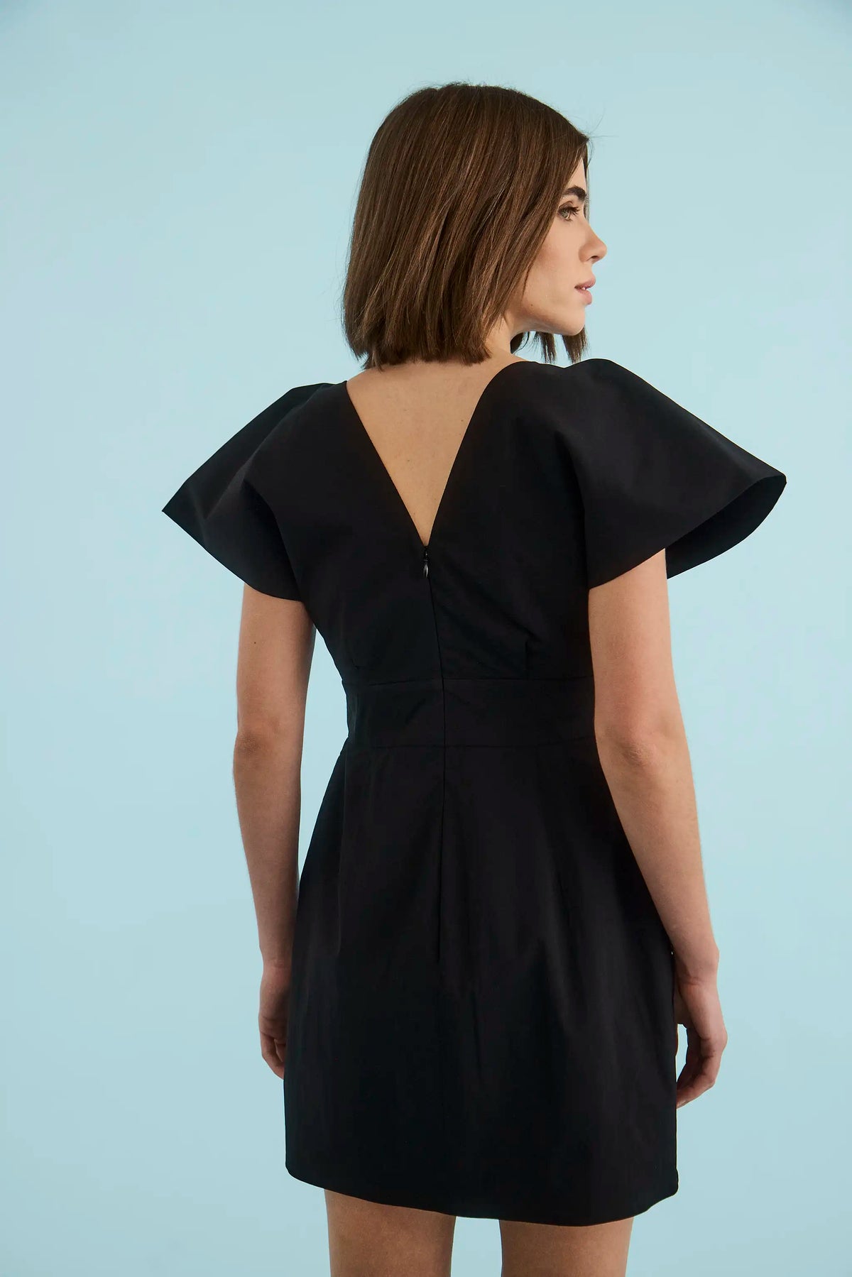 Model wearing black Hunter Bell Maris Dress with dramatic flutter sleeves and V-back detail