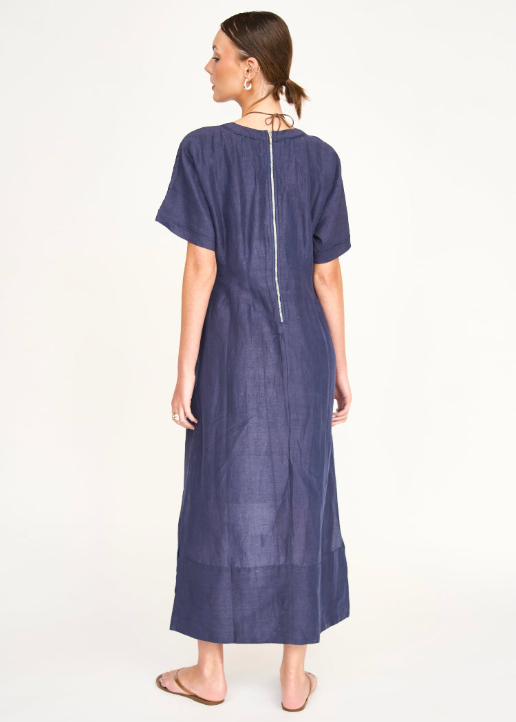 Woman wearing navy blue midi dress with short sleeves and back zipper, shown from behind