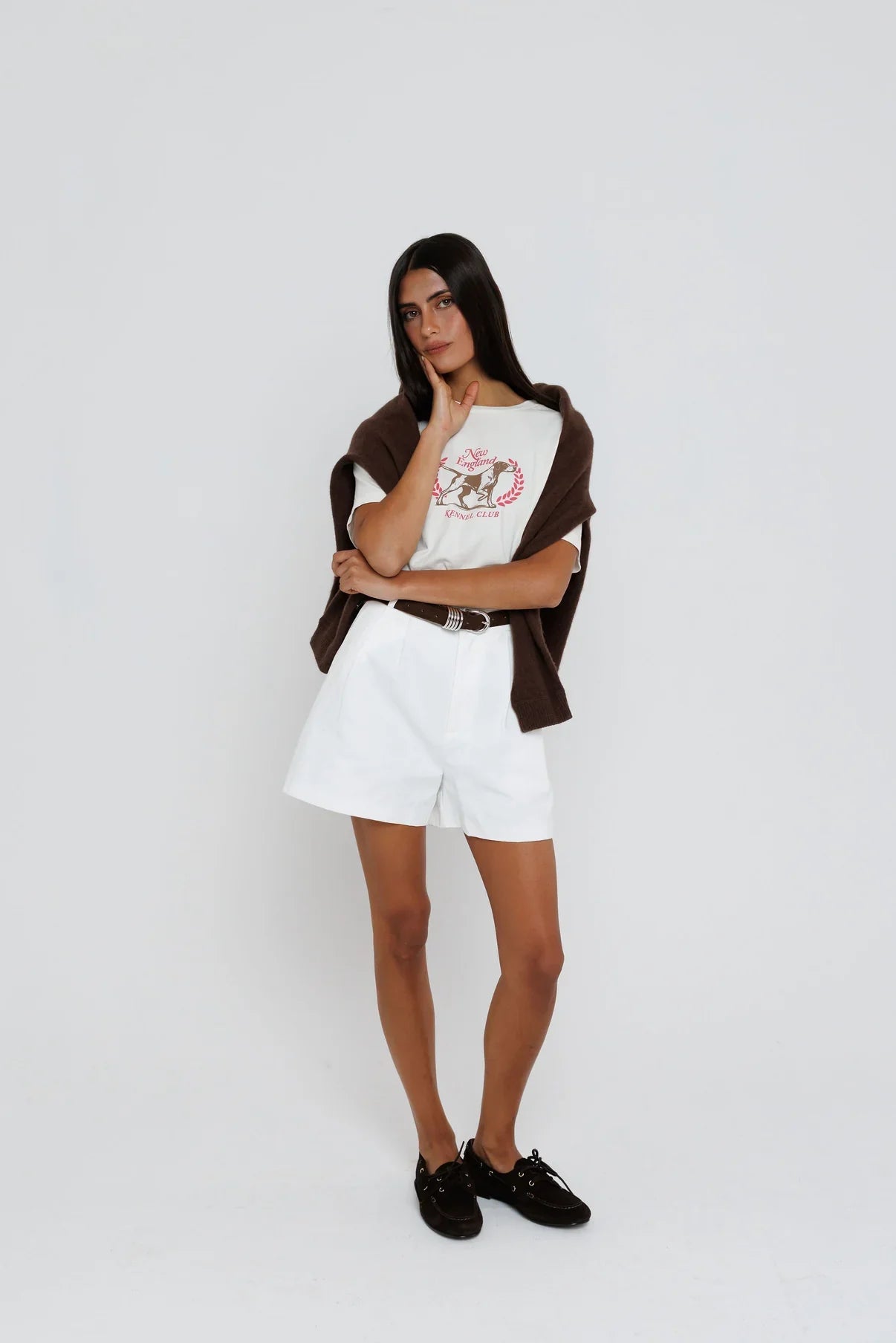 Model wearing white New England Kennel Club graphic tee with brown cardigan and white shorts
