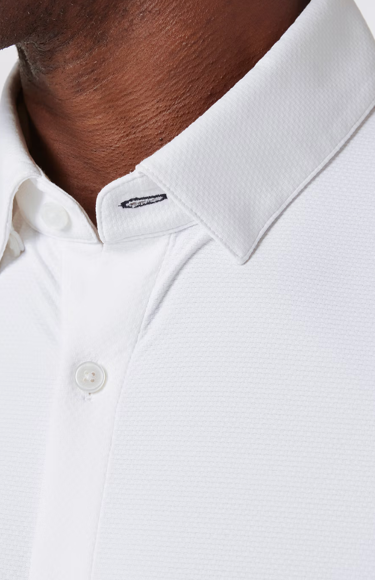 Close-up of Mizzen + Main white long sleeve dress shirt collar and button detail on model