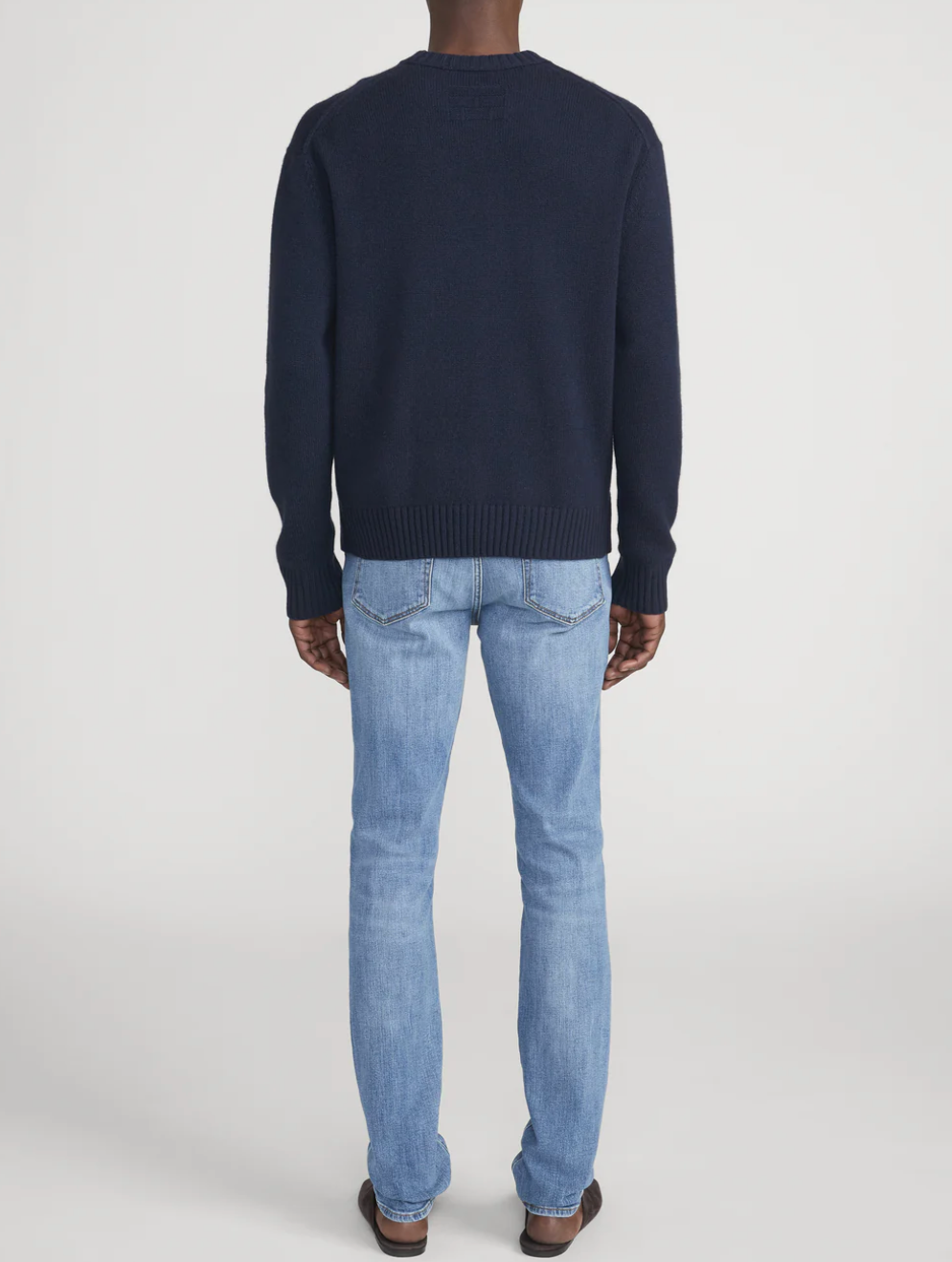 Frame L'Homme Slim jeans in light blue wash, shown from behind on male model wearing dark sweater.