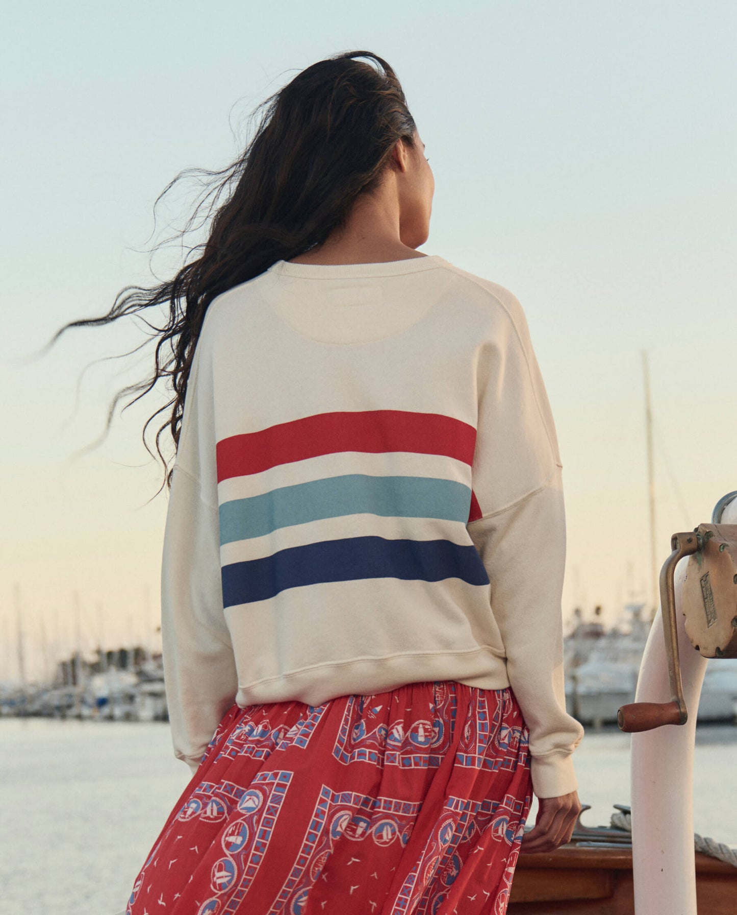 Woman wearing white sweatshirt with horizontal red blue stripes viewed from behind