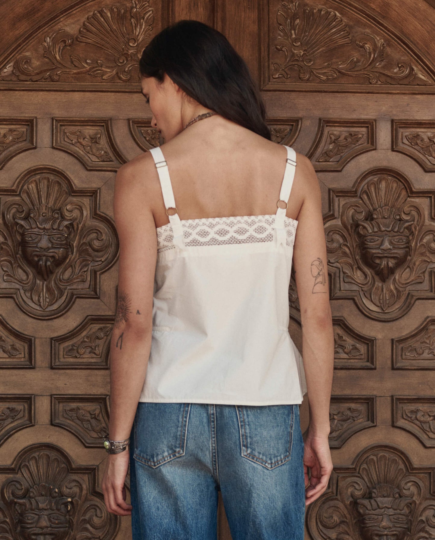 Back view of white Victorian tank top with lace trim and adjustable straps on model