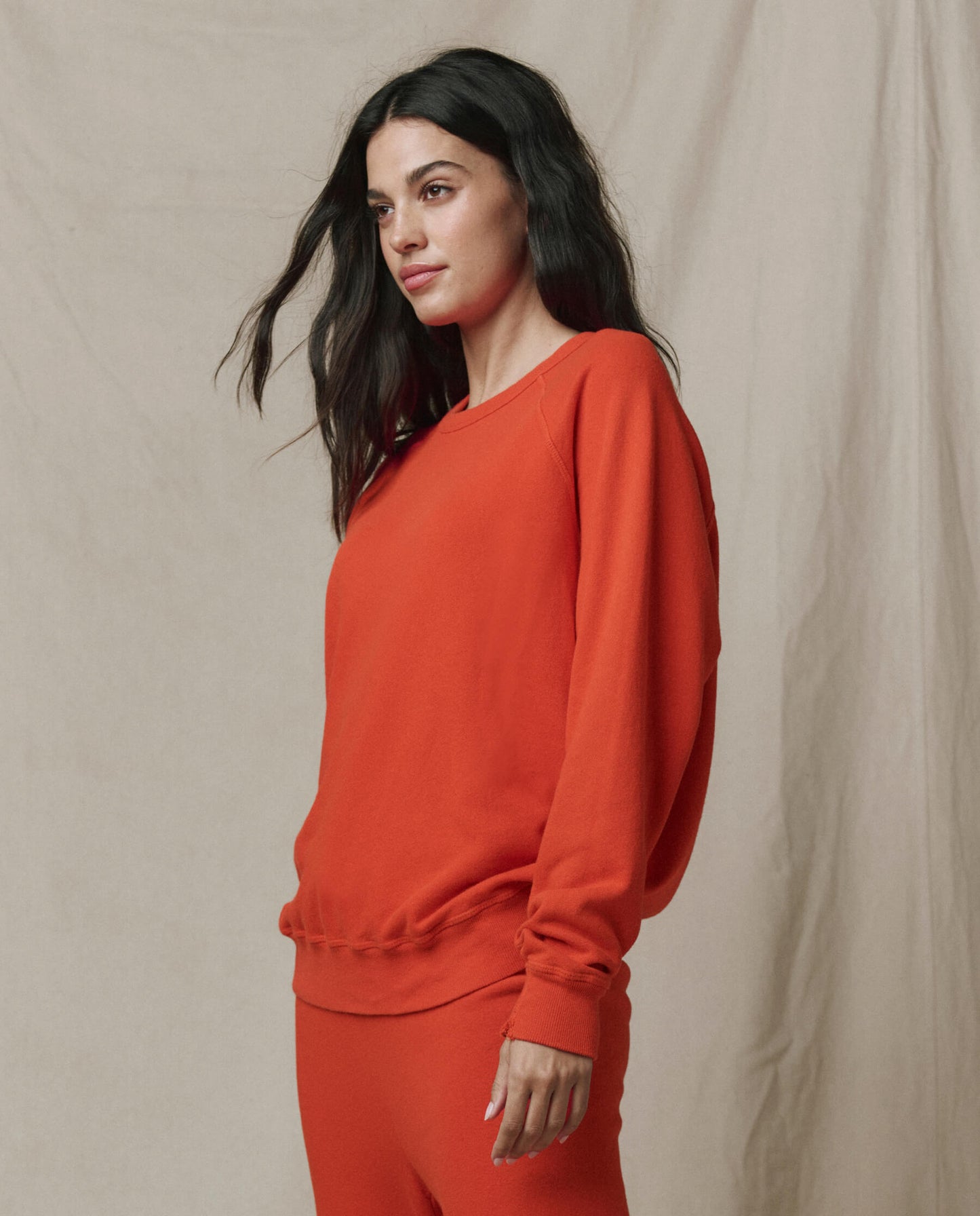Woman wearing orange-red persimmon college sweatshirt in professional lifestyle shot