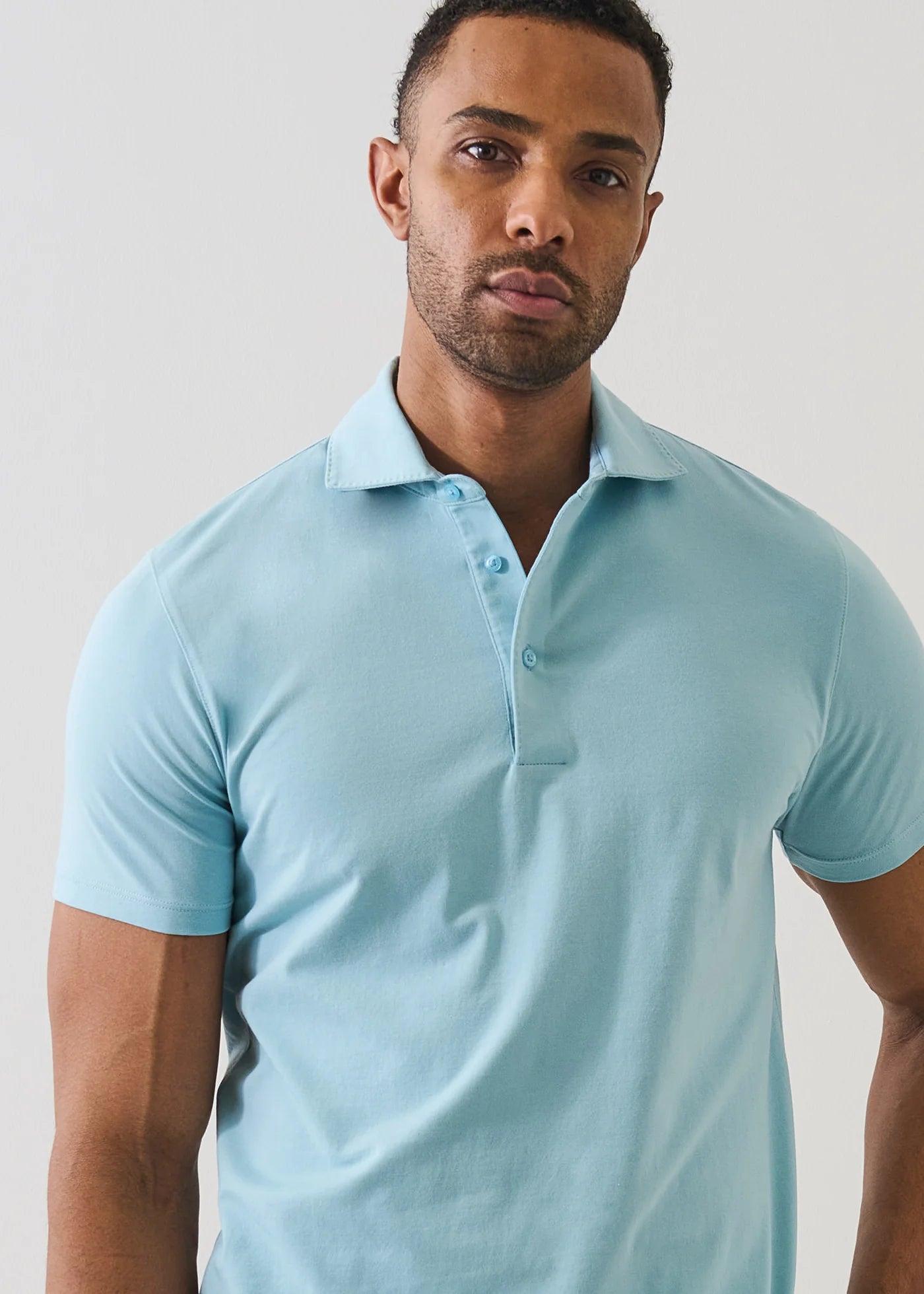 Man wearing Patrick Assaraf short-sleeve light blue pima cotton polo shirt with collar and button placket.
