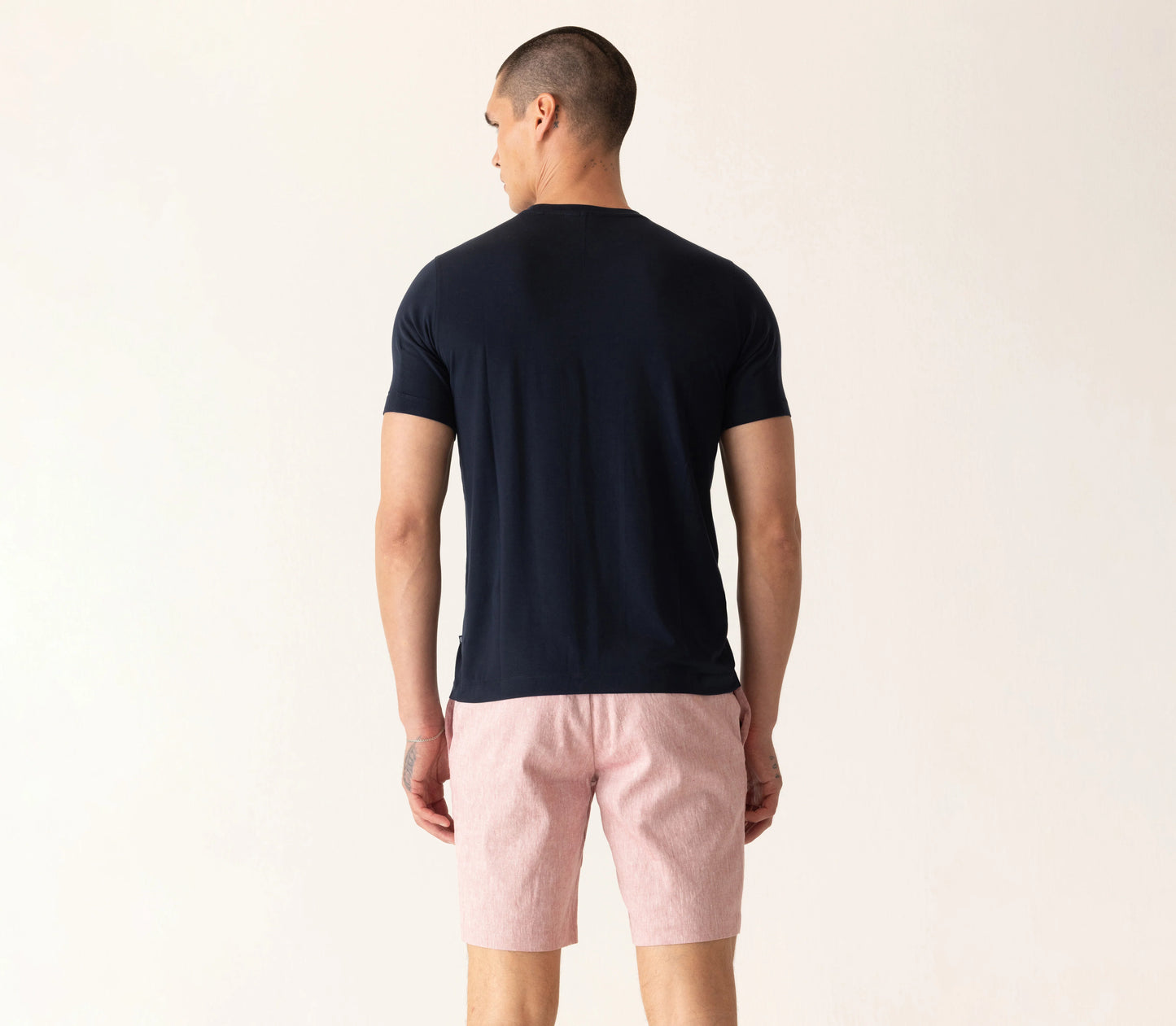 Man wearing Deke SS Modern Crew T-Shirt in midnight navy with pink shorts, shown from behind.