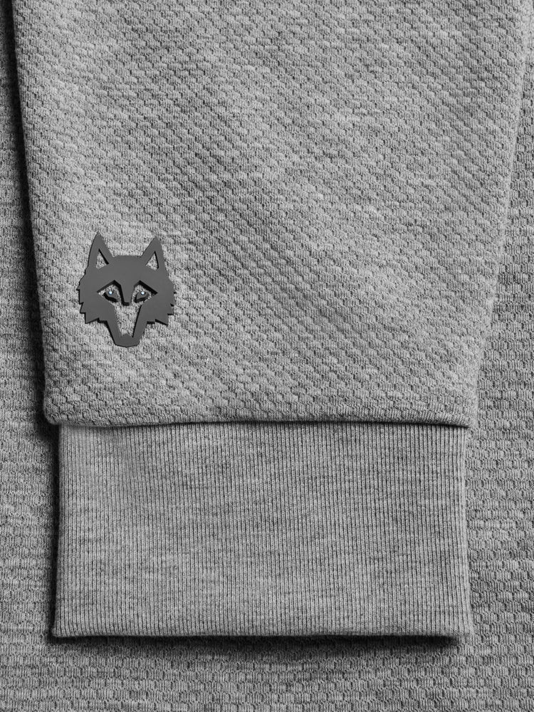 Close-up of grey heather jogger sleeve cuff with geometric wolf logo patch