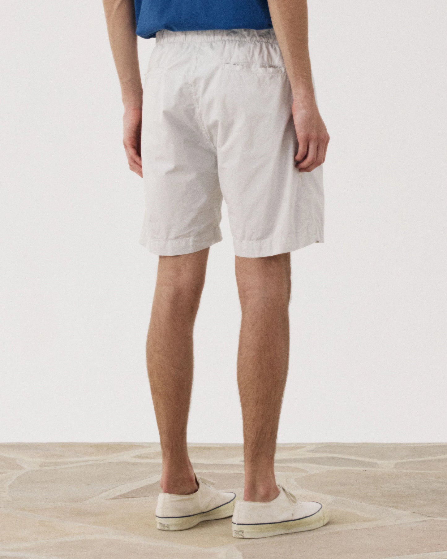 Hartford Joggy Short Flax - lightweight elastic waist shorts worn with blue top and white sneakers, back view