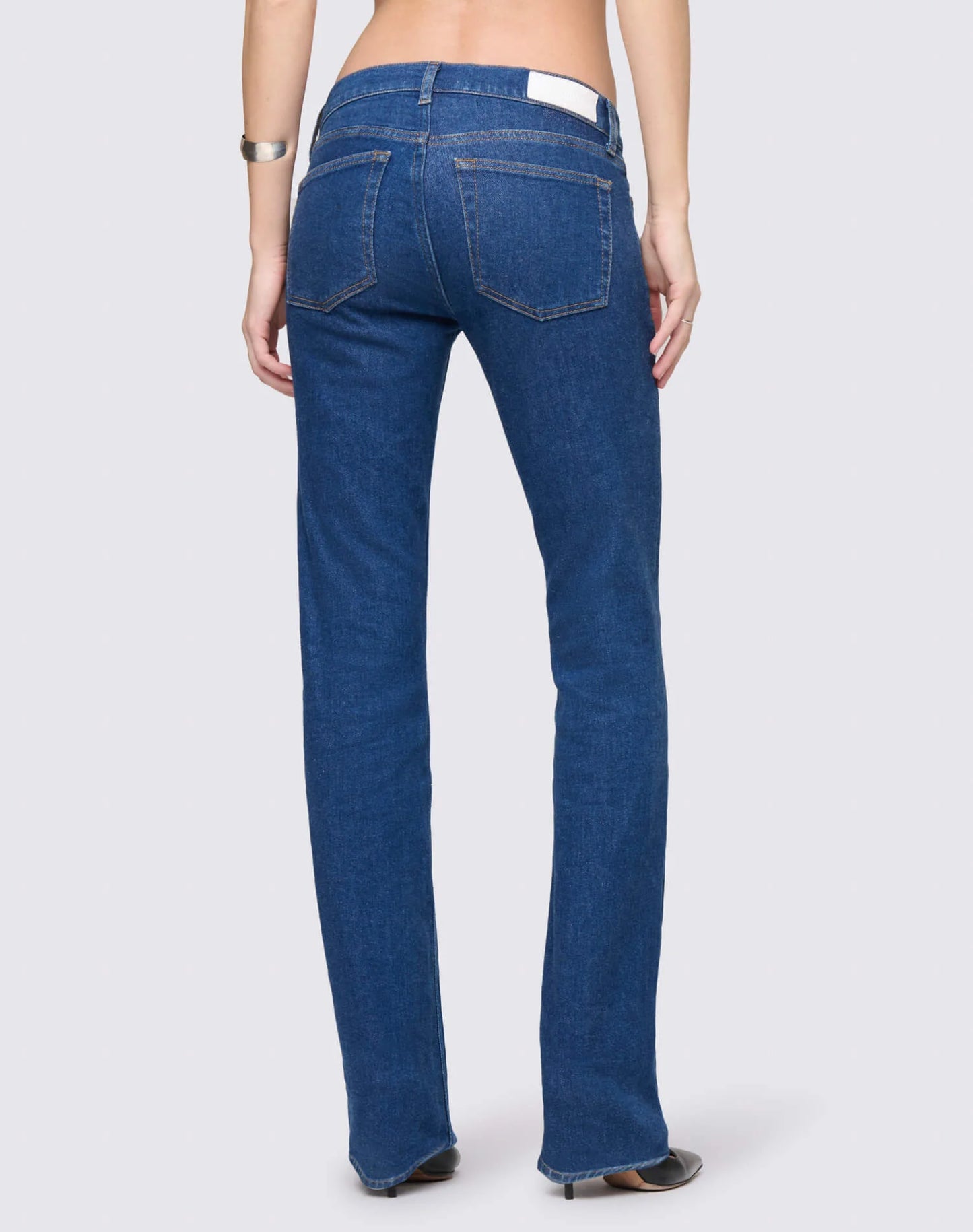 Woman wearing Re/Done dark blue straight-leg jeans with white label, shown from behind in a studio setting.