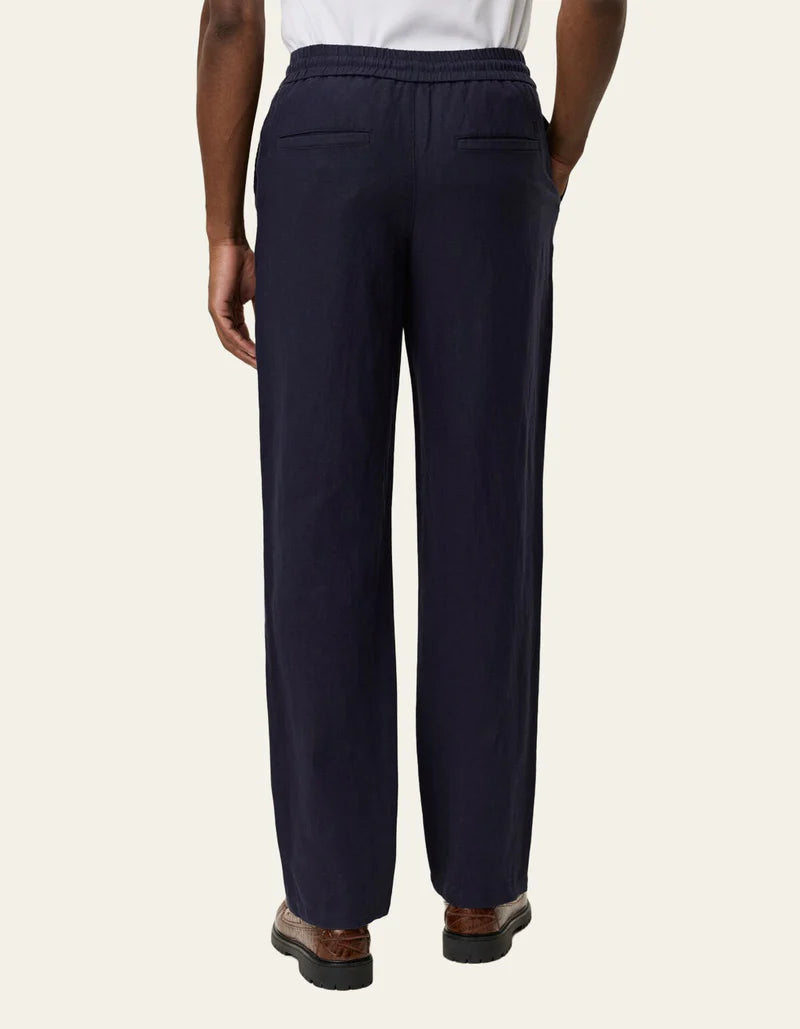 Les Deux Patrick navy linen pants shown from behind, featuring elastic waistband, back pockets, and relaxed straight-leg fit.