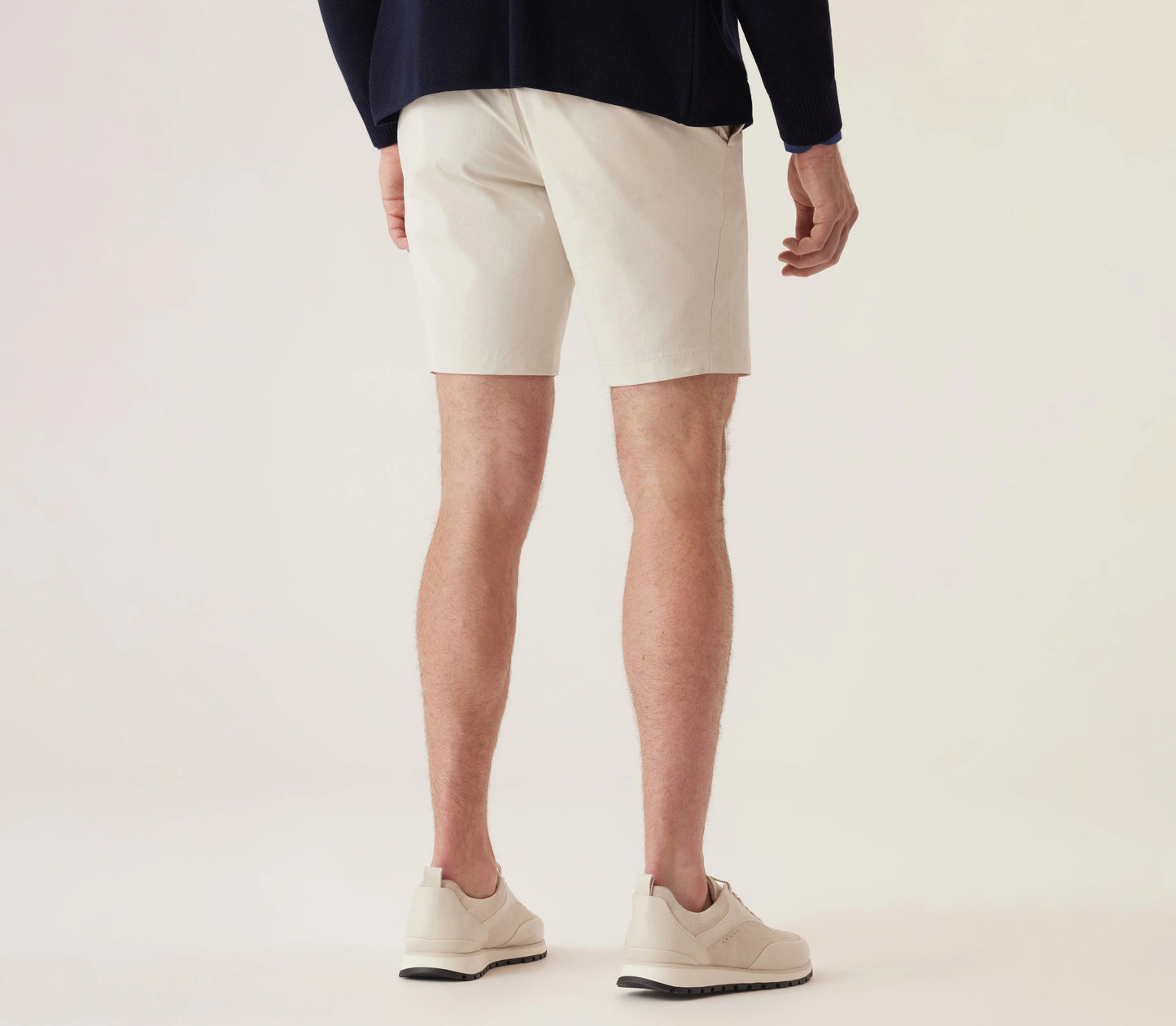 Man wearing light-colored Deke Galaxy Bermuda shorts in Ultra 4X Stretch Twill with casual sneakers.
