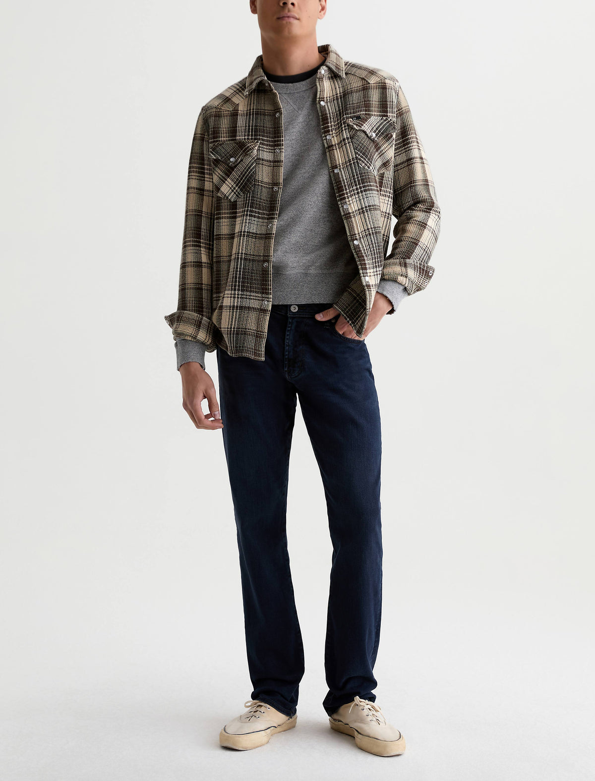 Male model wearing AG Graduate tailored leg jeans in dark indigo with plaid flannel shirt