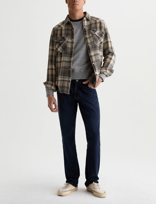 Male model wearing AG Graduate tailored leg jeans in dark indigo with plaid flannel shirt