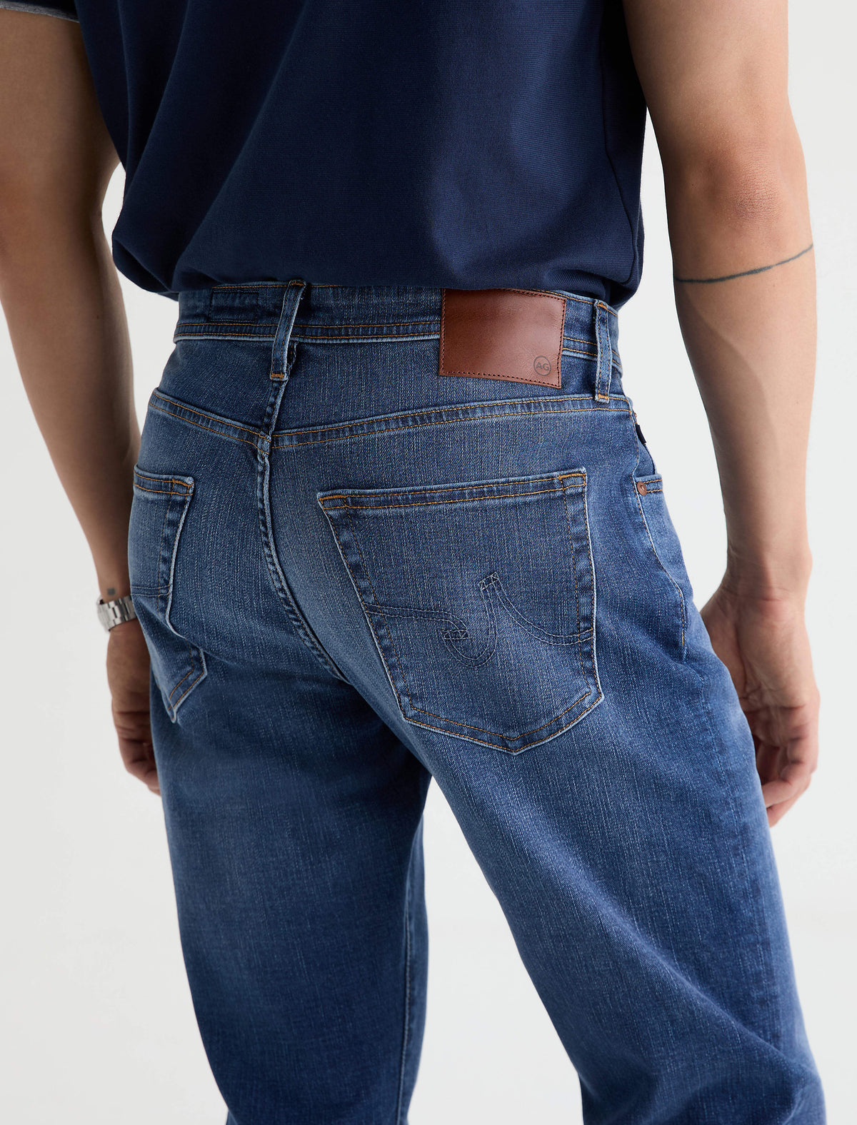 Back view of AG Graduate jeans in medium blue wash with brown leather patch
