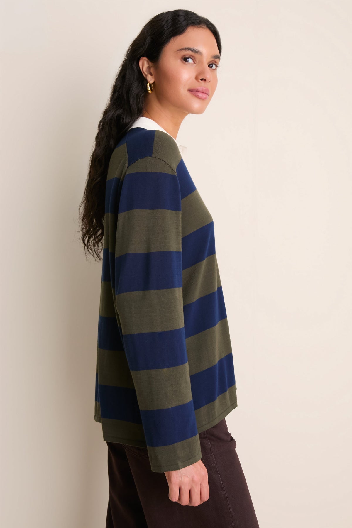 Model wearing olive and navy wide-stripe long-sleeve polo sweater with white collar