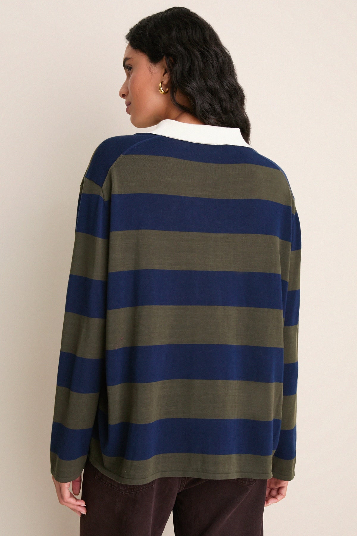 Back view of model wearing olive and navy striped long-sleeve polo sweater with white collar