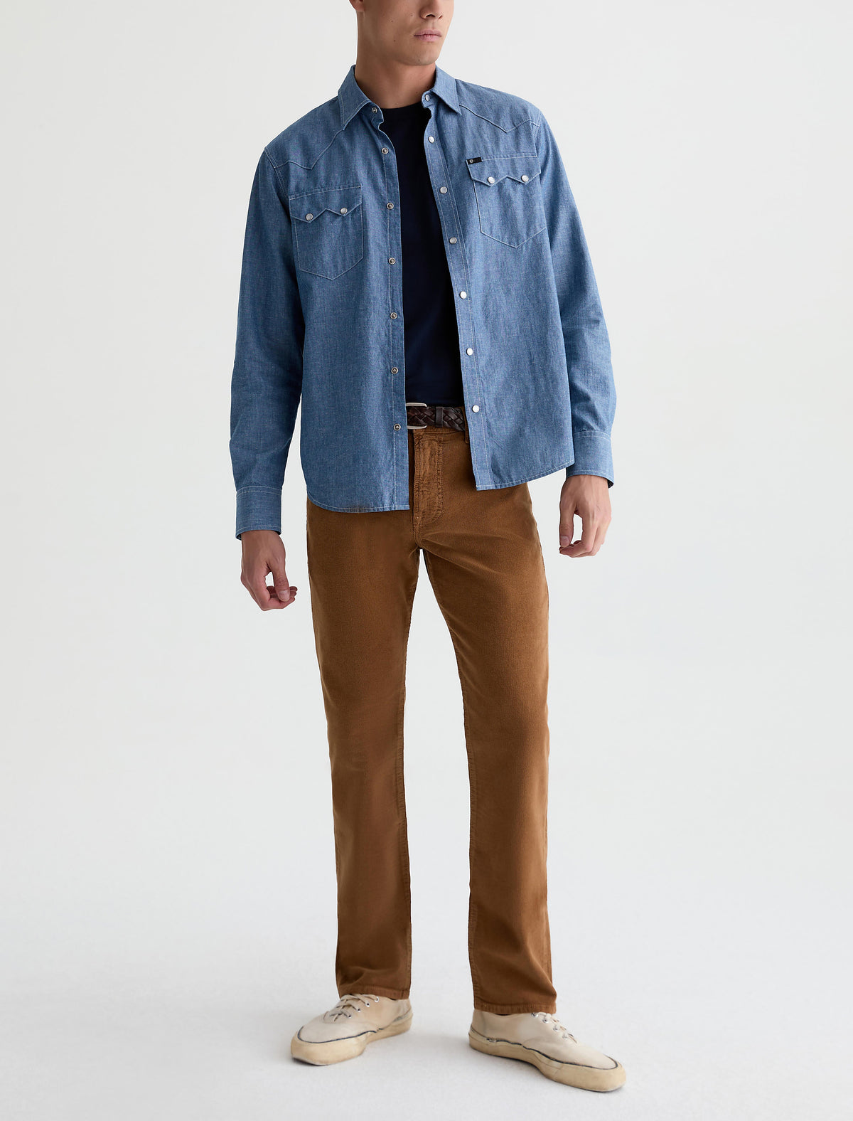 Male model wearing AG Everett straight corduroy pants in bronze beat with denim shirt