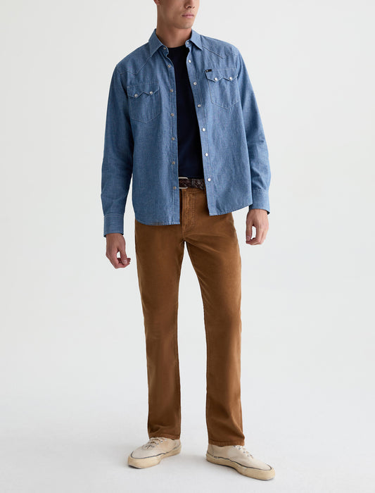 Male model wearing AG Everett straight corduroy pants in bronze beat with denim shirt