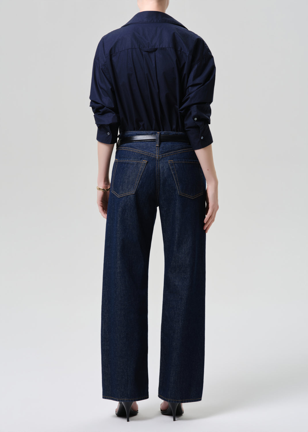 Back view of wide-leg dark indigo jeans with navy shirt and belt