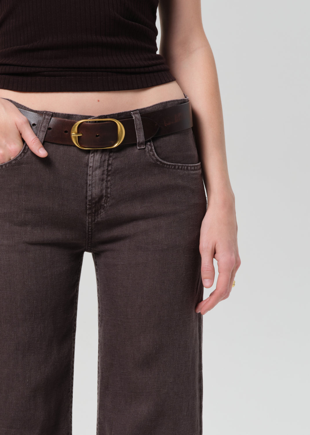 Model wearing charcoal gray linen trousers with brown leather belt and gold buckle