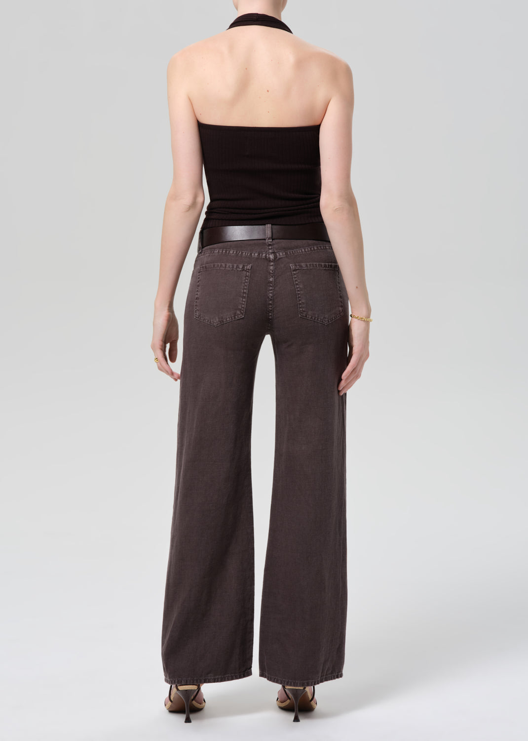Woman wearing charcoal wide-leg trouser jeans and black halter top, back view
