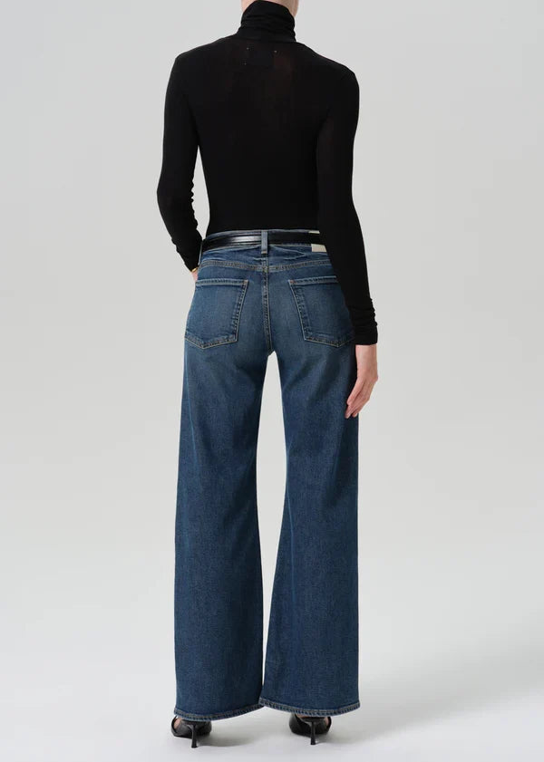 Back view of wide-leg dark indigo jeans with black turtleneck top and heels
