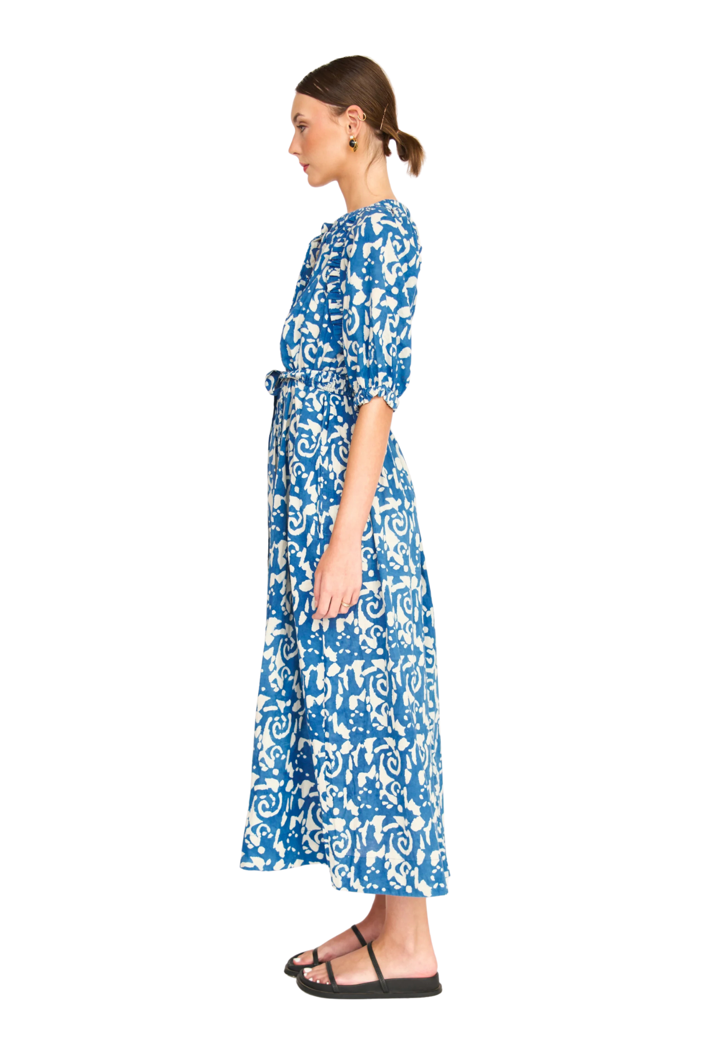 Woman in profile wearing blue and white patterned maxi dress with belt