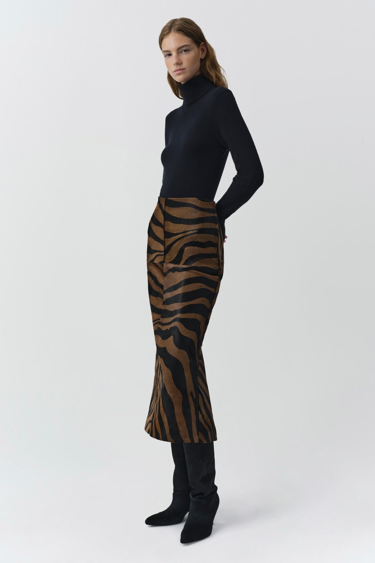Model wearing black cashmere turtleneck with fitted long sleeves on neutral background