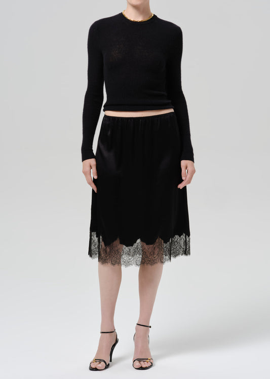Model wearing black lace-trimmed satin midi skirt with black knit crop top