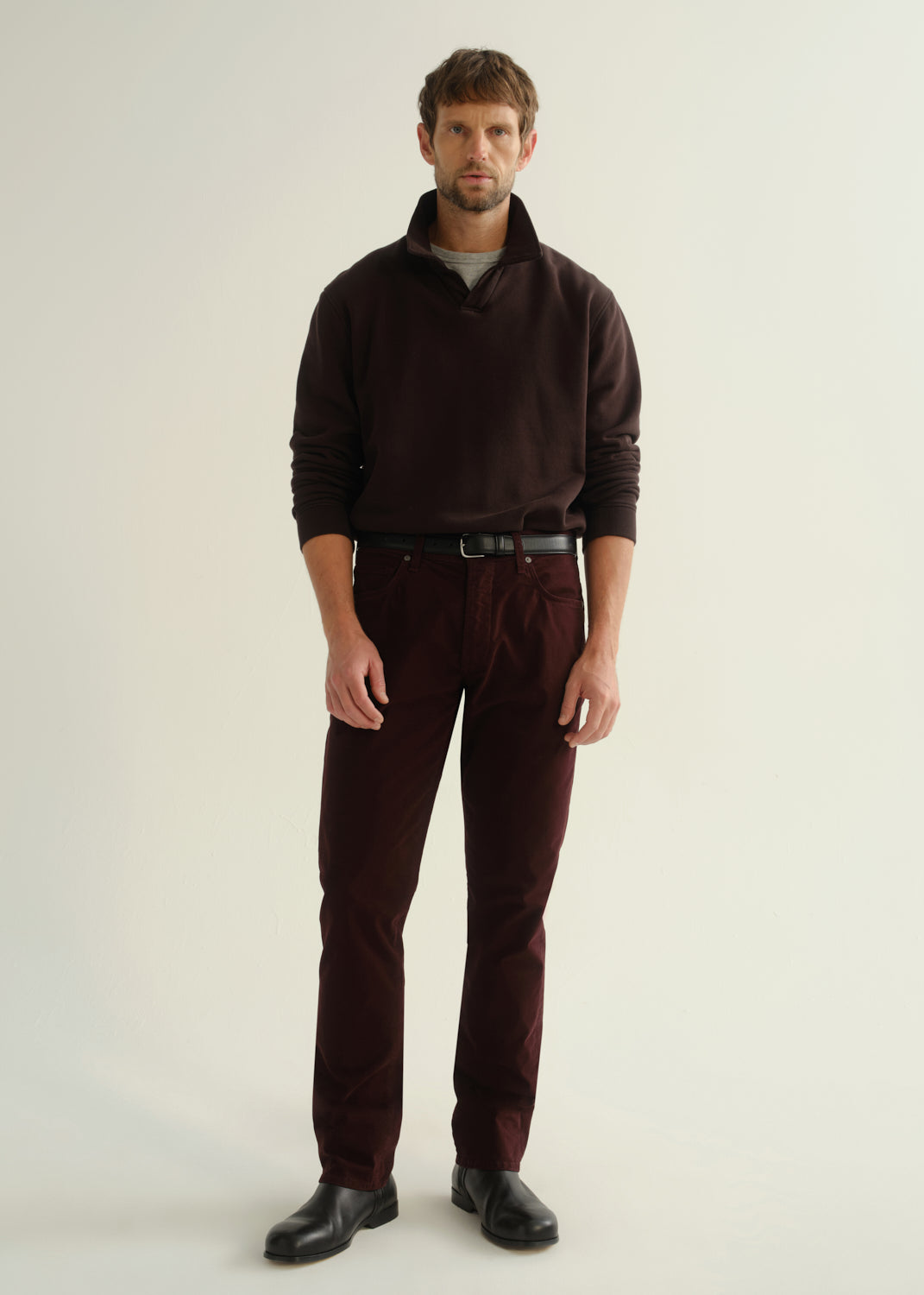 Male model wearing Citizens of Humanity Gage slim straight burgundy sateen pants with matching sweatshirt