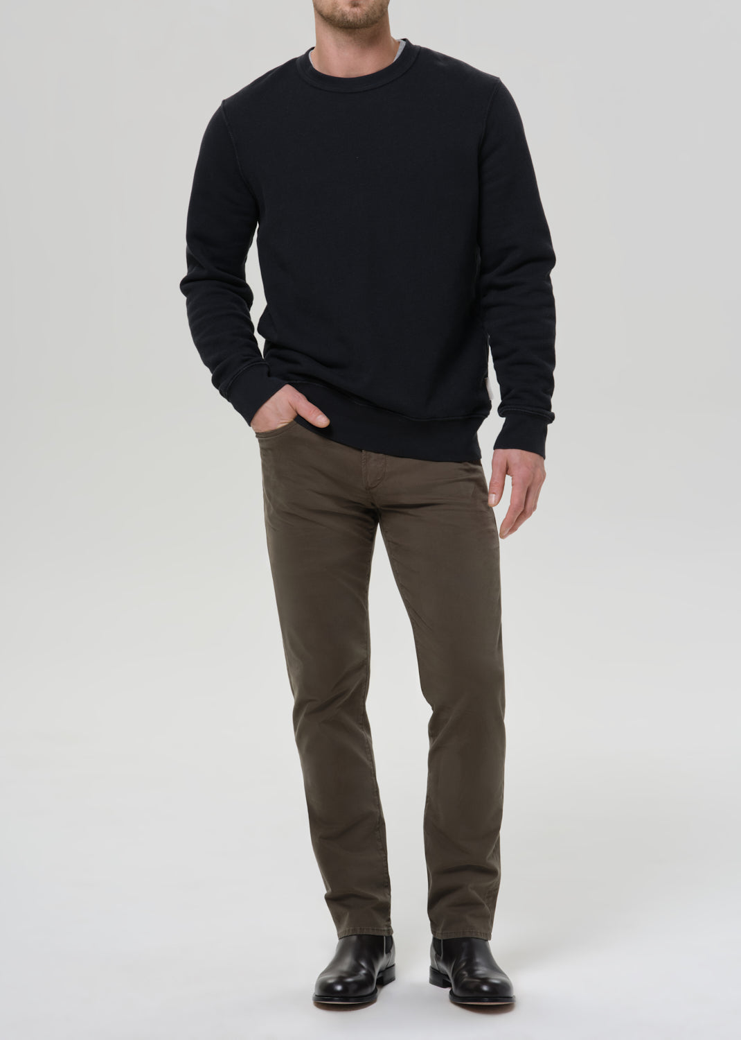 Male model wearing Citizens of Humanity Gage slim straight olive sateen pants with black sweatshirt