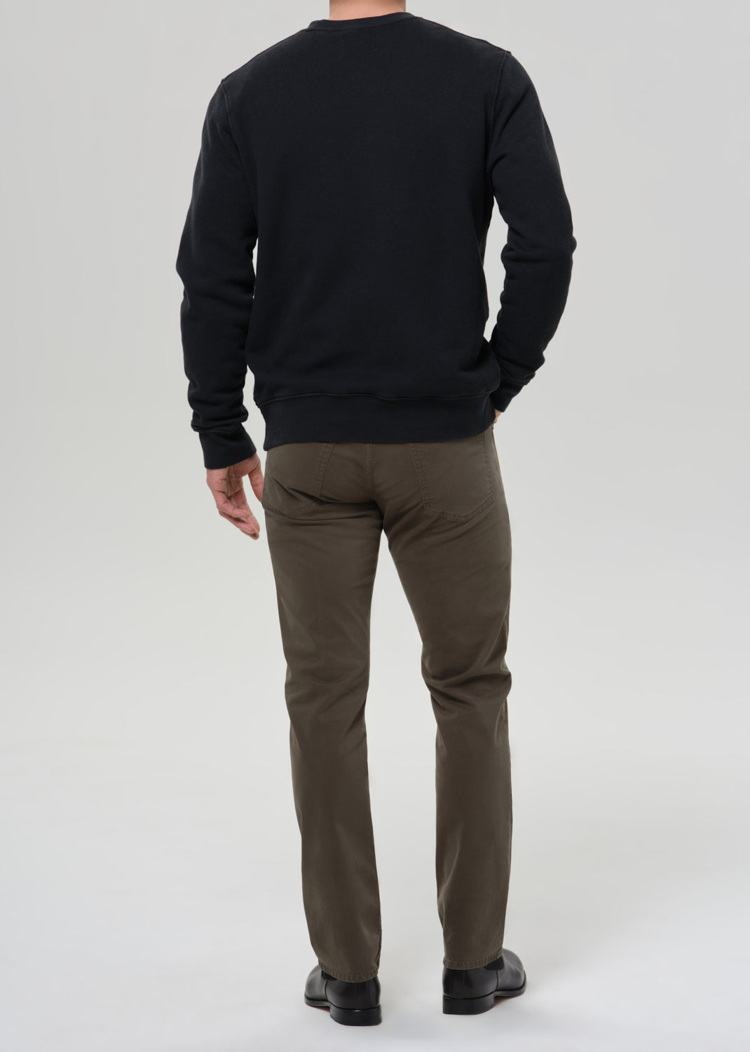 Rear view of male model wearing Citizens of Humanity Gage slim straight olive sateen pants