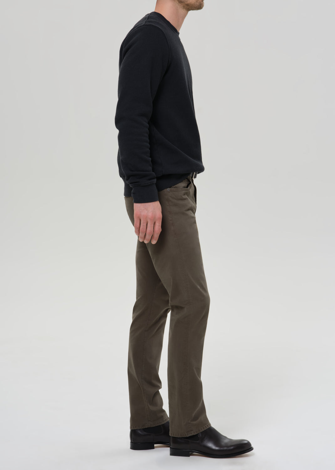 Male model wearing Citizens of Humanity Gage slim straight olive sateen pants with black sweatshirt