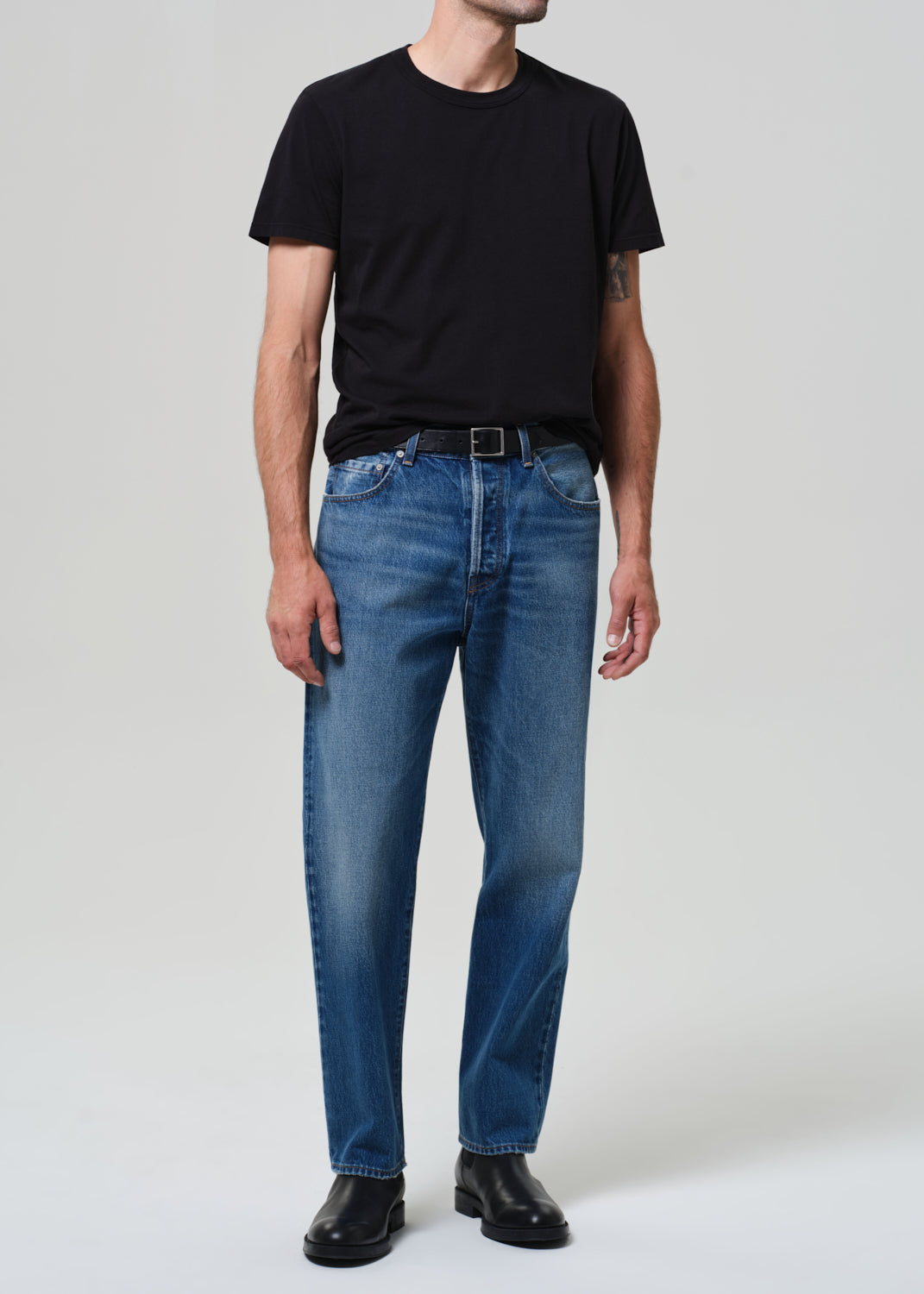Male model wearing Citizens of Humanity Beau straight leg jeans in mid blue with black tee