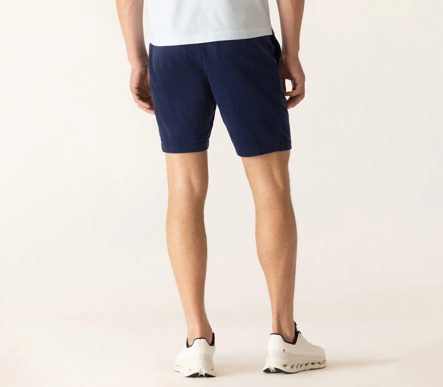 Back view of man wearing navy corduroy bermuda shorts with white sneakers