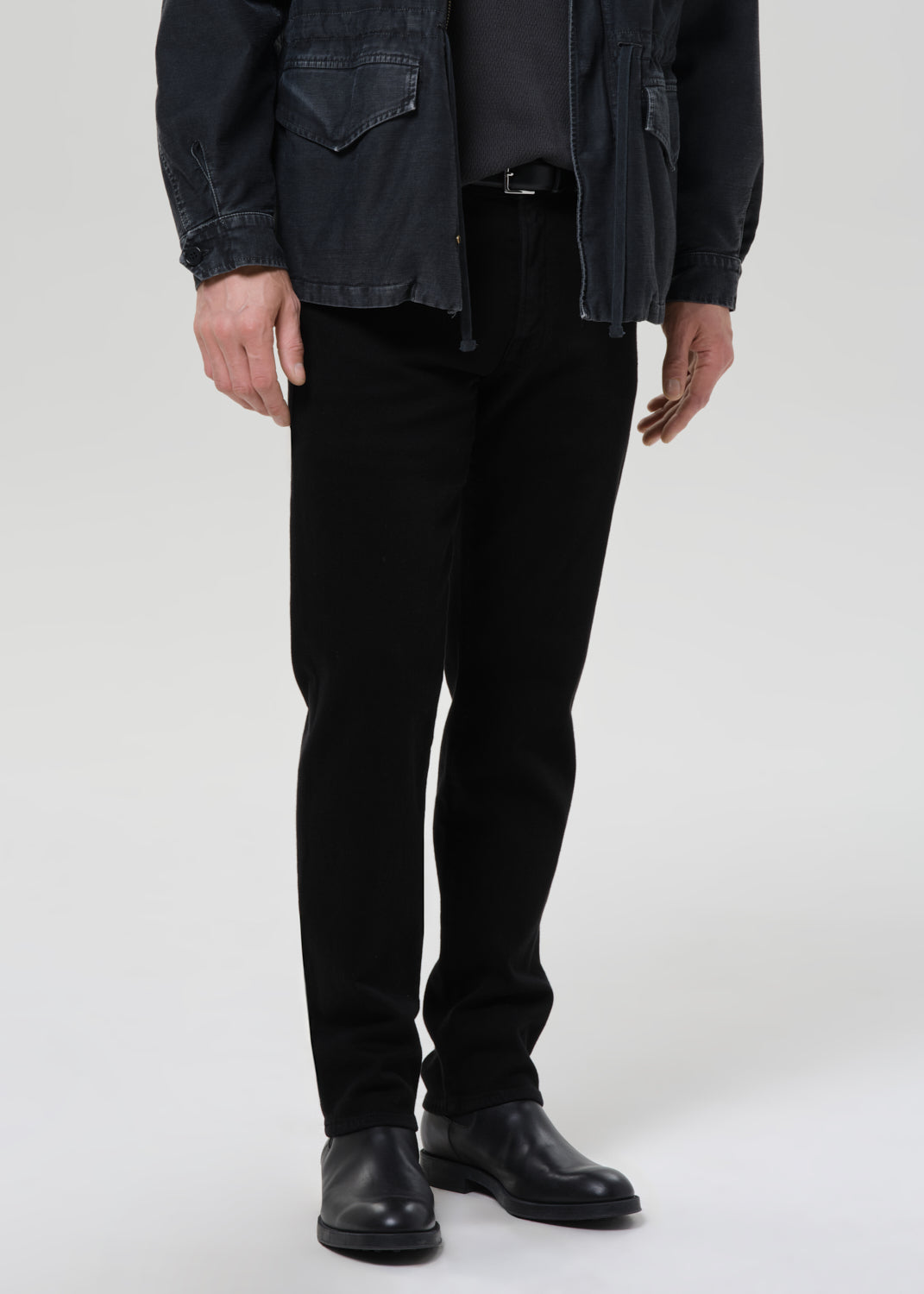Male model wearing Citizens of Humanity Elijah straight black jeans with dark jacket and leather boots