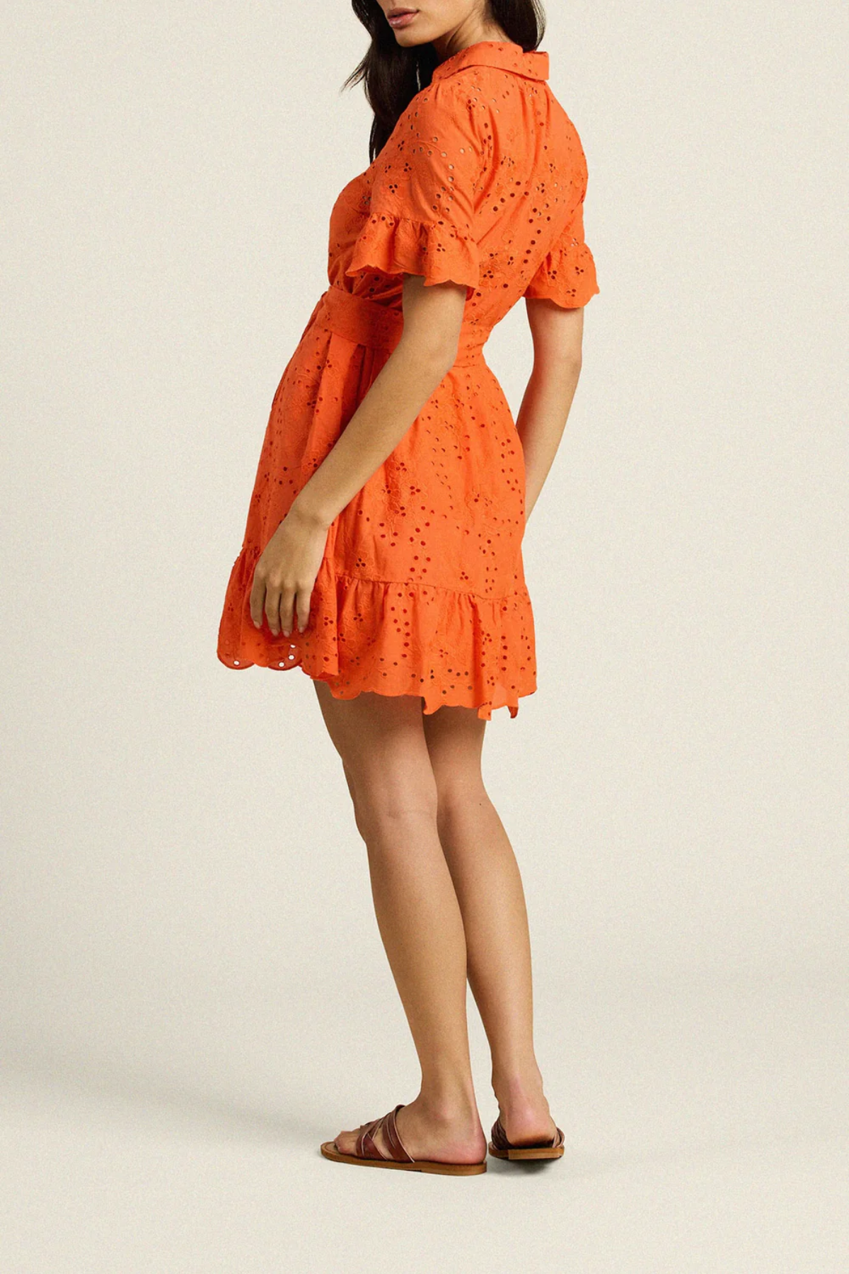 Woman wearing orange eyelet mini dress with ruffled sleeves and hem detail