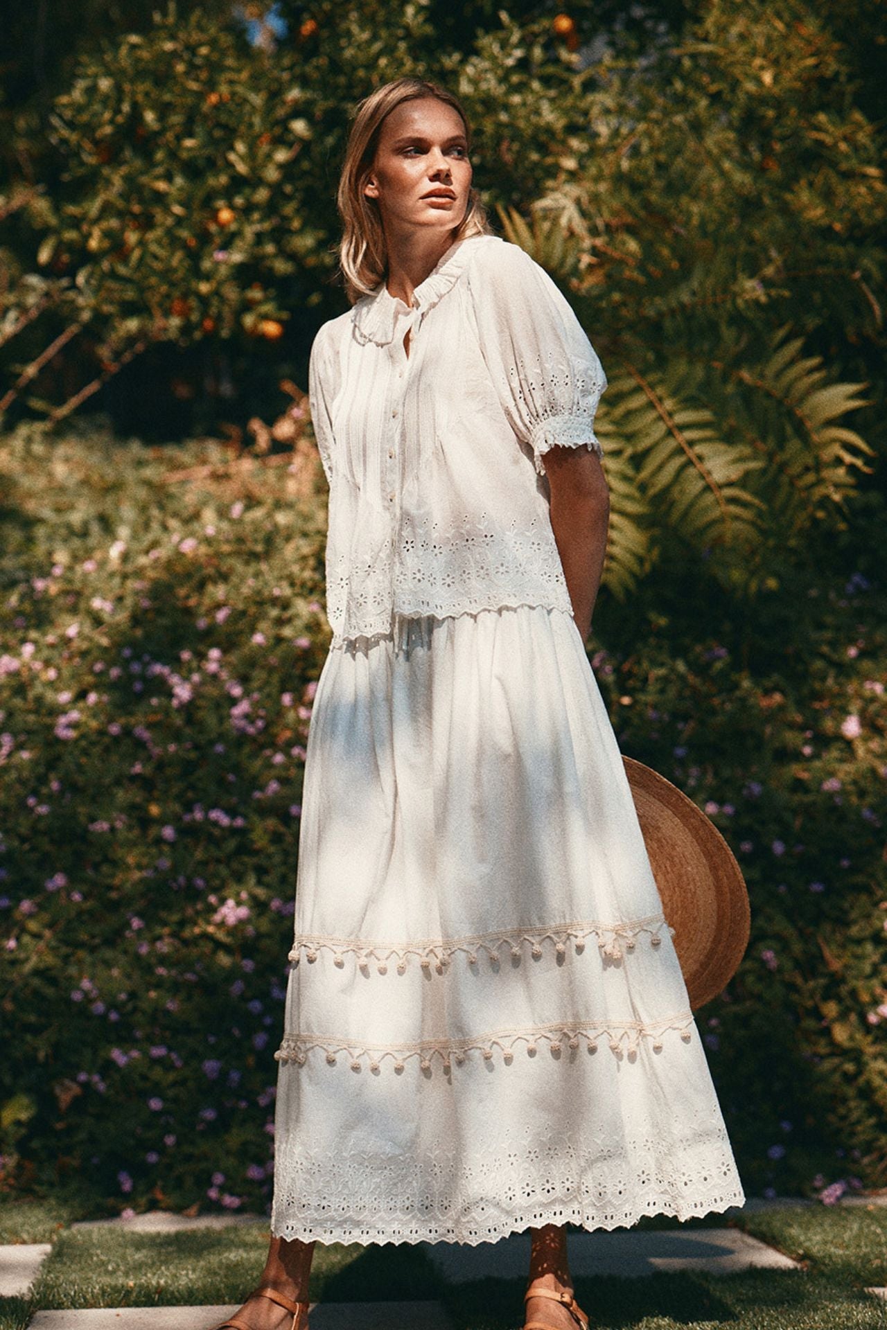 Woman wearing white eyelet blouse with lace trim details in garden setting