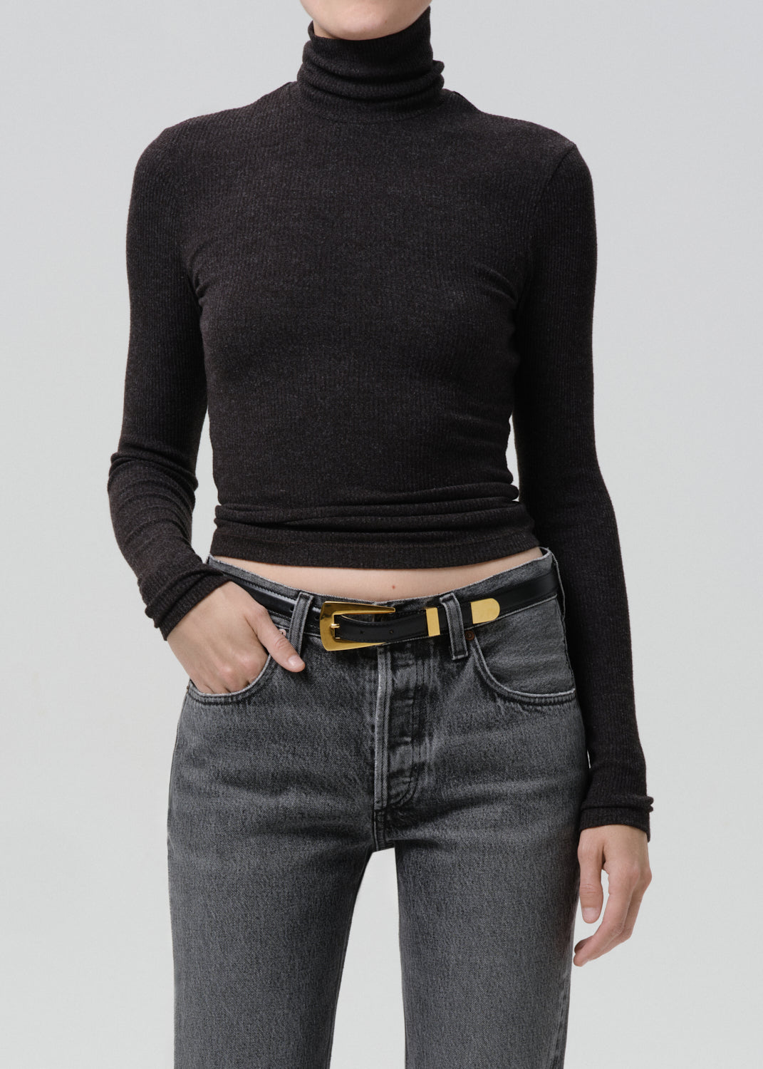 Model wearing a dark heather charcoal ribbed turtleneck cropped long-sleeve top with grey jeans