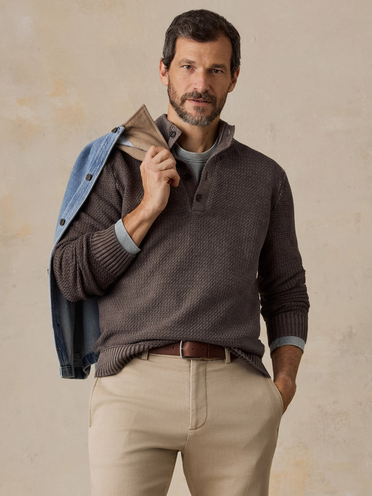 Male model wearing Faherty Sunwashed Dockside Quarter Button sweater in Coast Brown with khaki pants
