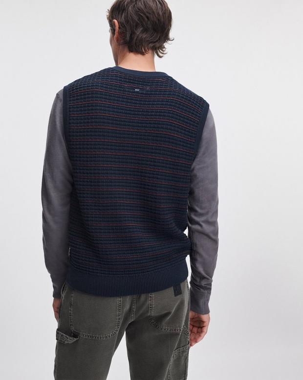 Back view of navy striped knit vest worn over grey long-sleeve shirt with cargo pants