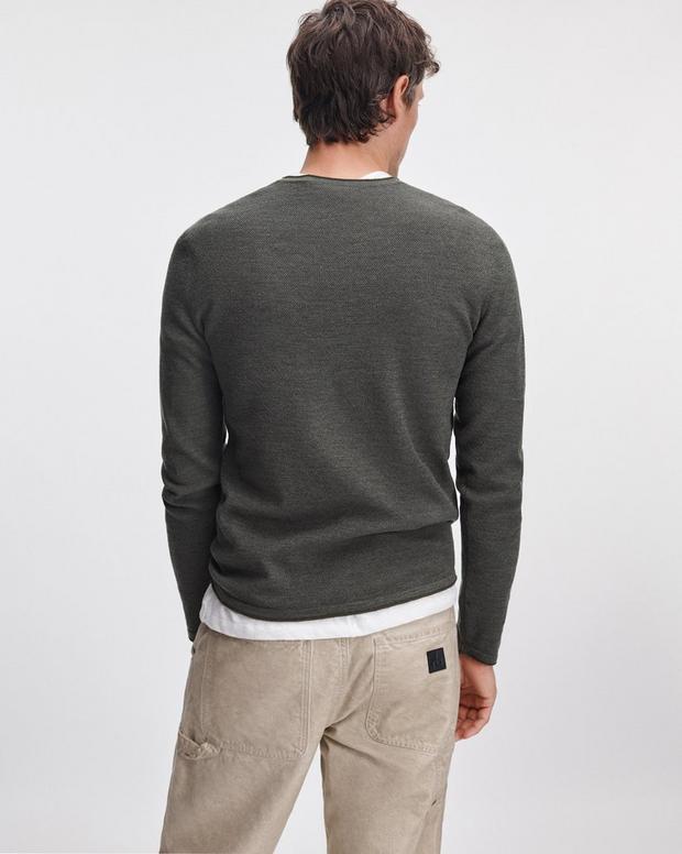 Back view of male model wearing olive green merino wool crewneck sweater with khaki pants