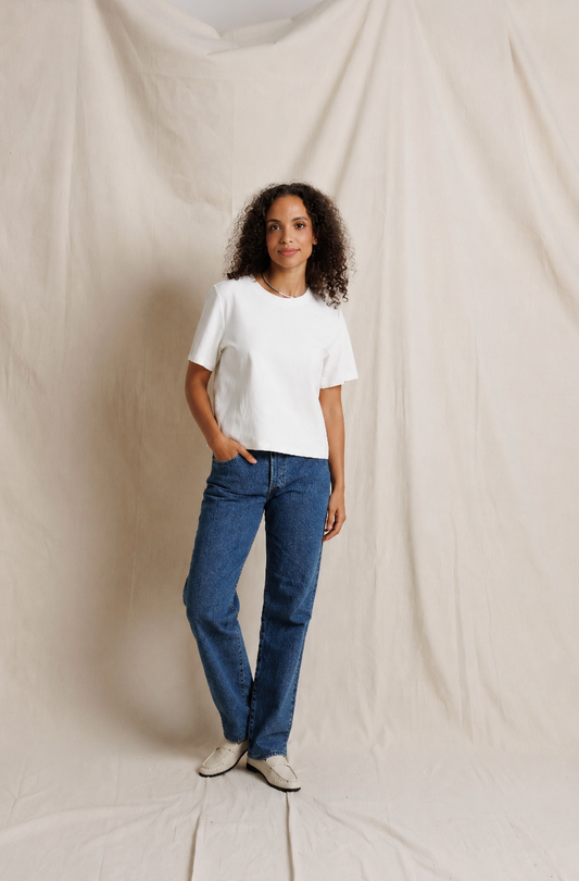 Model wearing white crewneck heavy cotton tee with blue straight-leg jeans and white loafers
