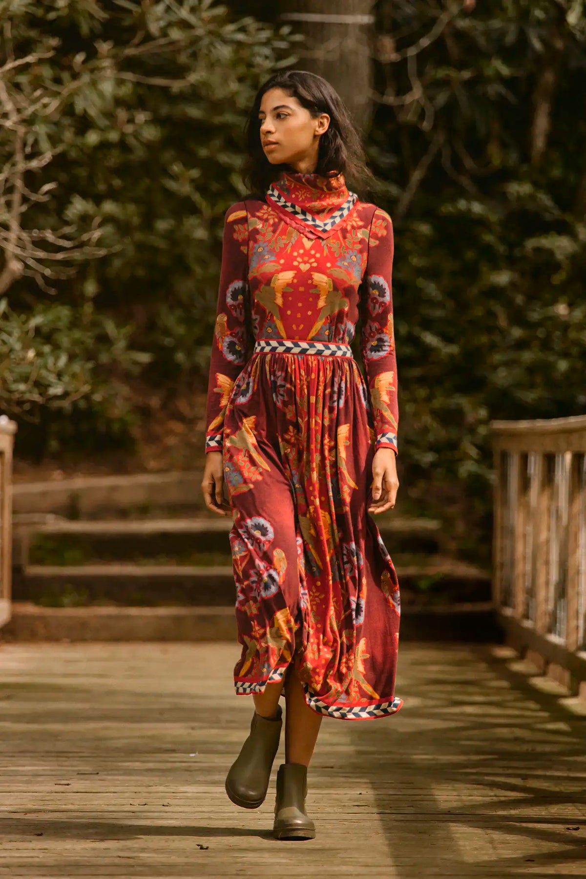Model wearing Hunter Bell Wimberly Skirt in maroon birds of a feather floral print with matching top on wooden bridge